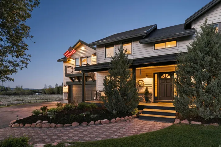 Siding exterior with stone accents, covered front porch, dark-paned windows, and a brick paver pathway
