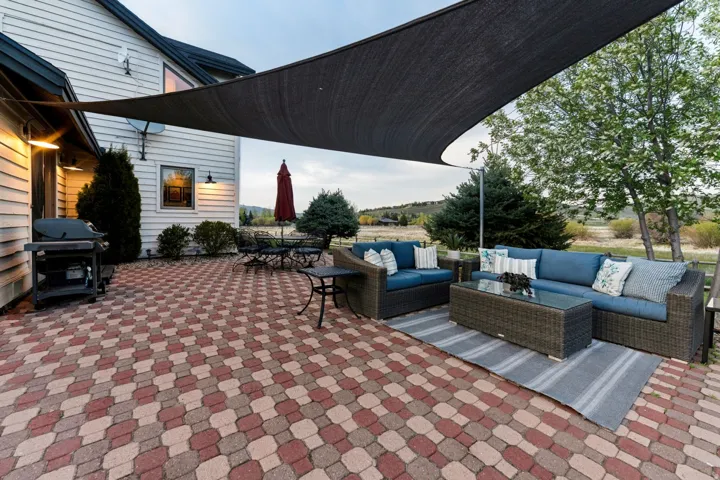 Expansive paver patio with a multi-tone pattern, shaded by a large sun sail