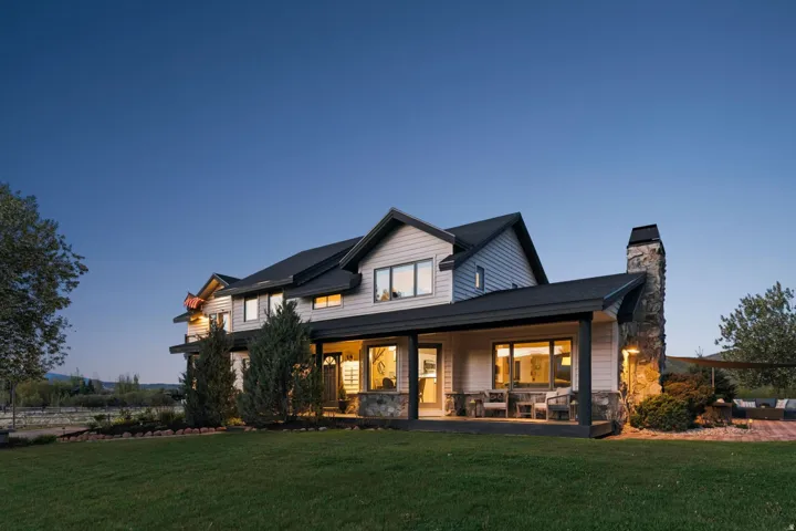 Two-story siding exterior with stone accents, a covered front porch, and a stone chimney