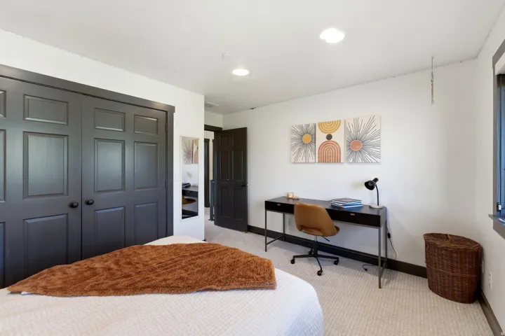 Built-in closet with dark paneled doors, recessed lighting, carpet flooring, and dark-trimmed window