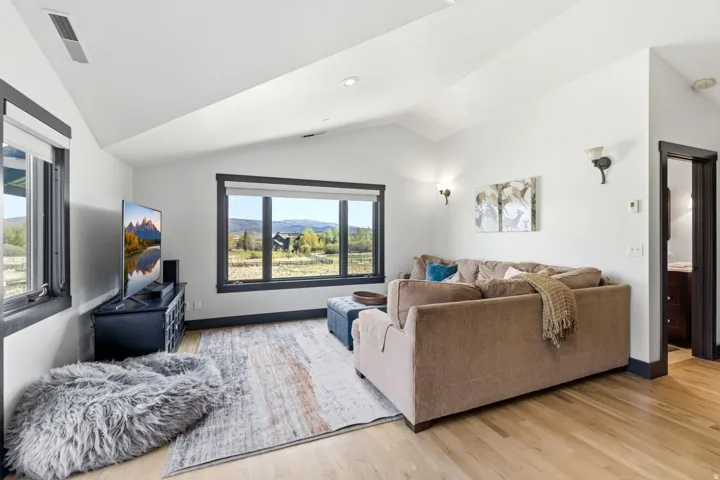 Vaulted ceilings, light wood-finish flooring, recessed lighting, and wall sconces