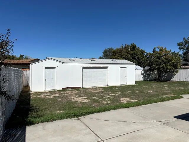 Detached outbuilding with multiple access doors, a roll-up garage door, and rooftop skylights
