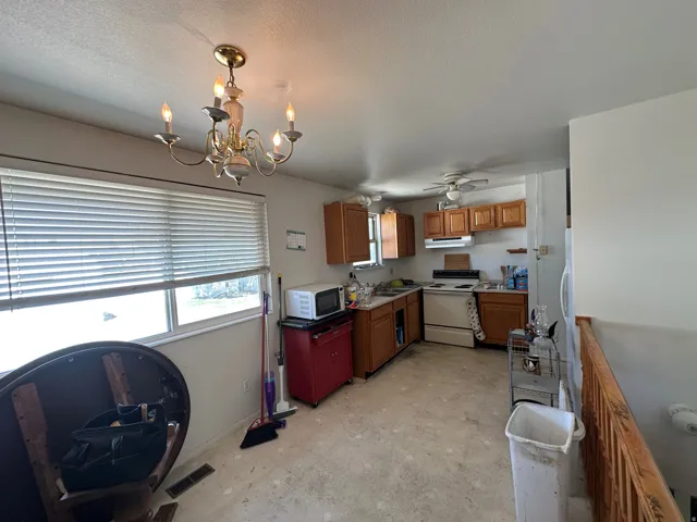 Kitchen featuring wood cabinetry, ceiling fan, and a four-light chandelier