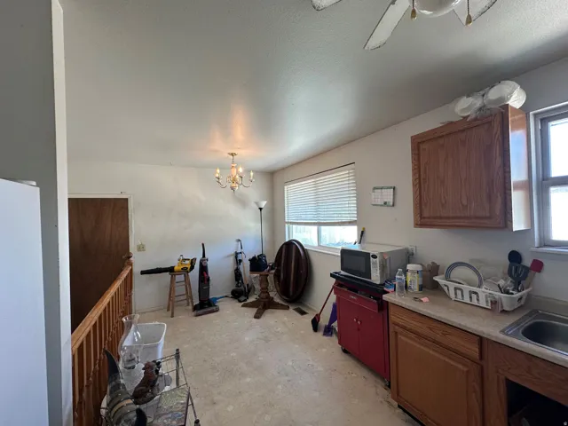 Kitchen area featuring wood-finish cabinetry, a stainless steel sink, and a window with blinds