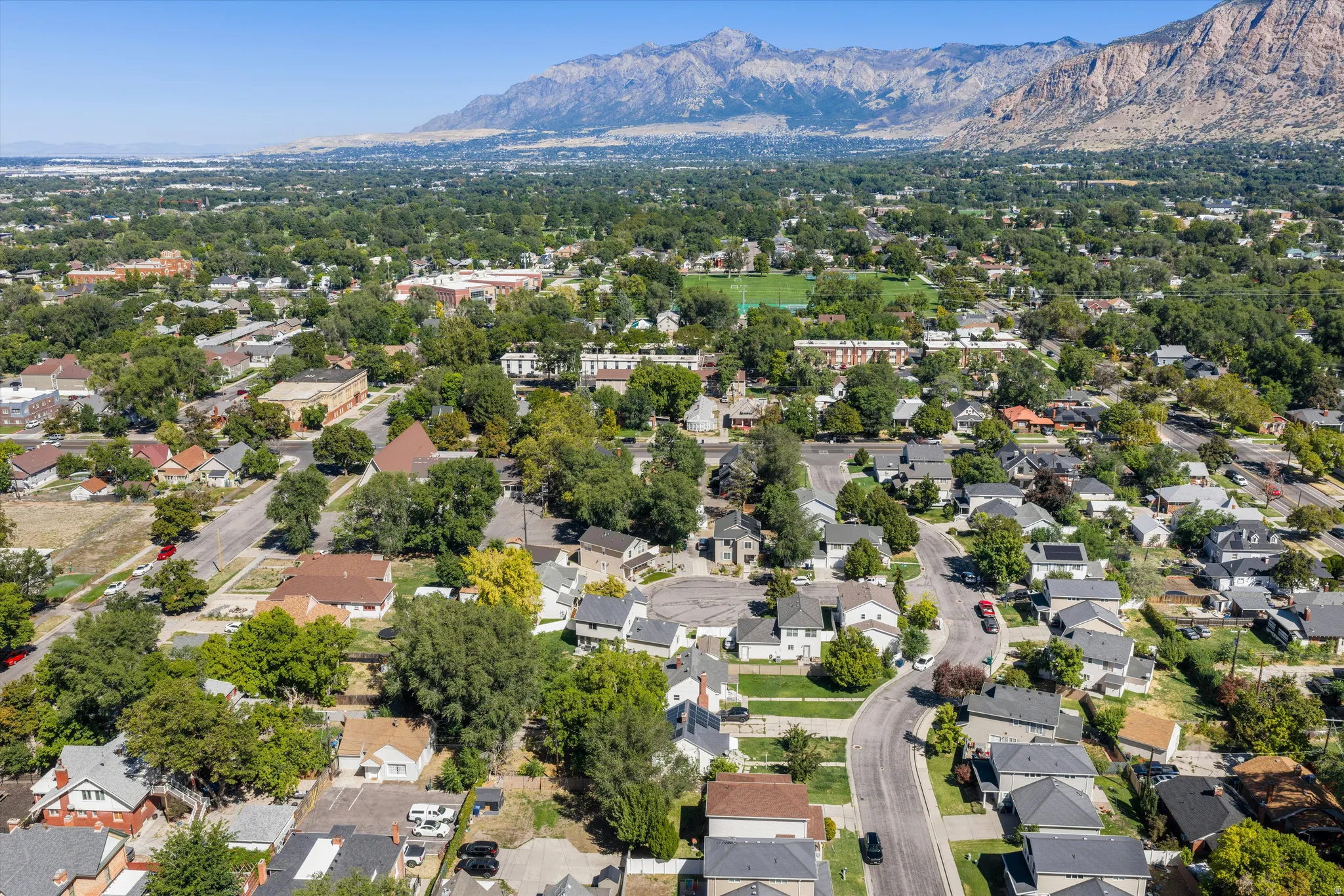 Residential neighborhood with varied rooflines and mature tree coverage, framed by distant mountains