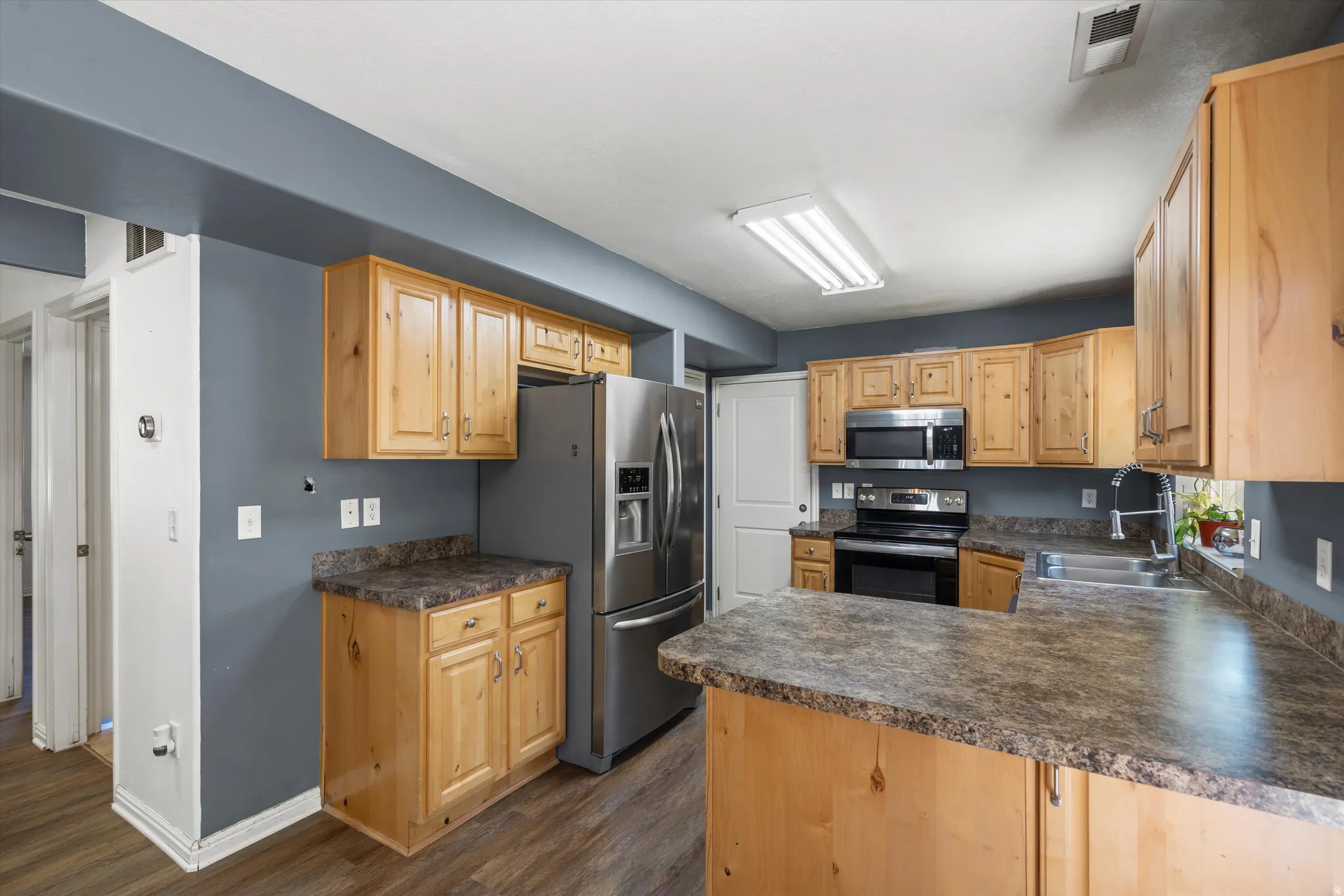 Kitchen featuring wood cabinetry, stainless steel appliances, and wood-finish flooring
