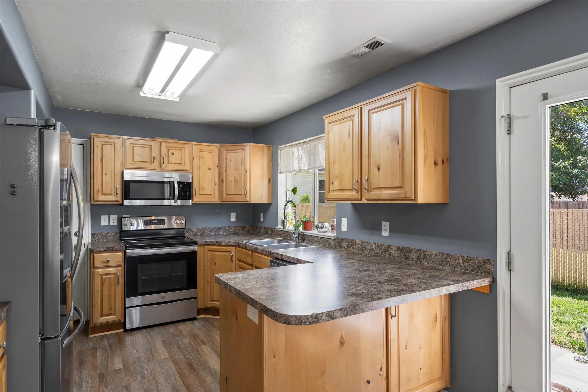 Kitchen featuring wood cabinetry, stainless steel appliances, a double basin sink, and wood-finish flooring