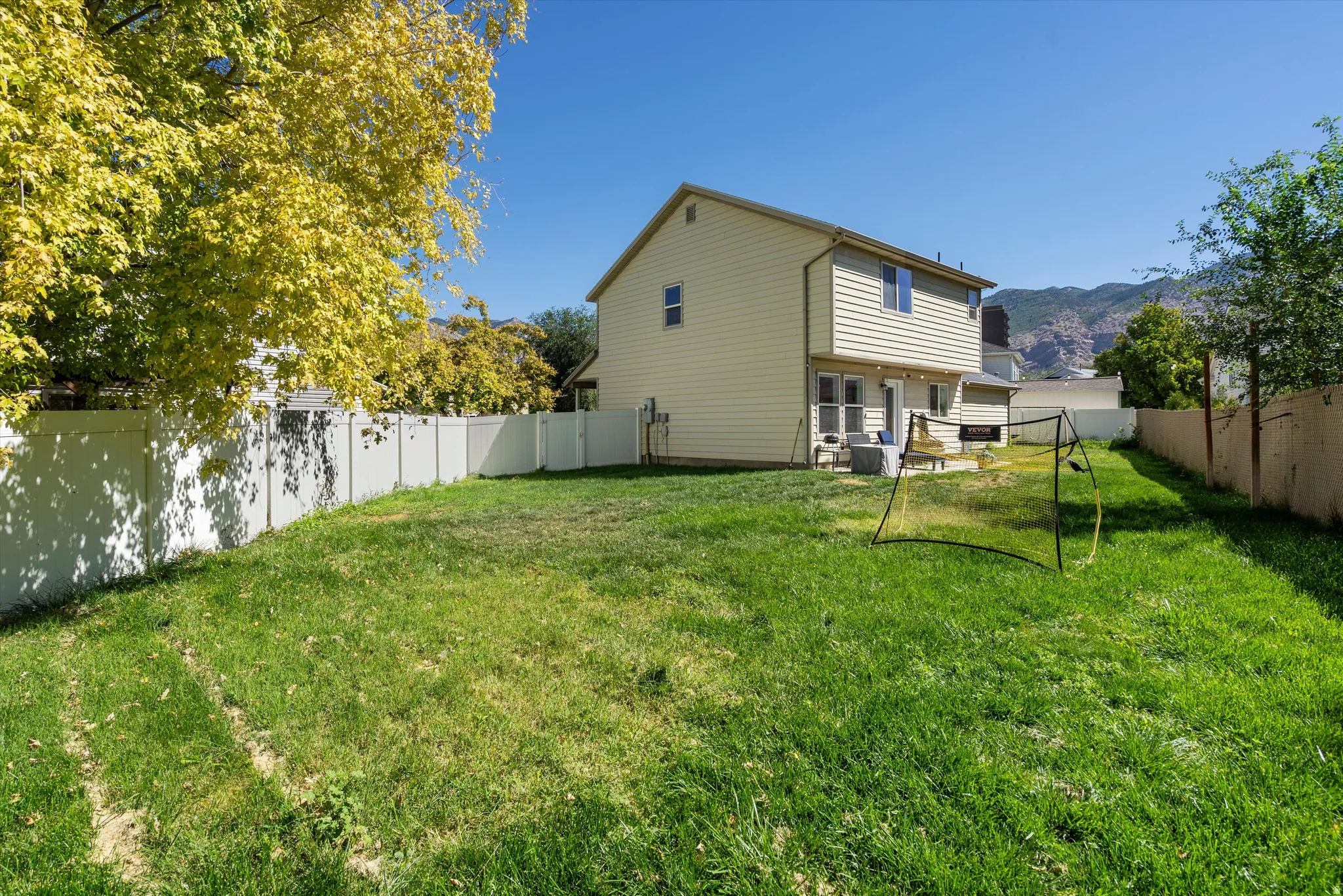 Expansive grassy yard with full vinyl fencing and a two-story home exterior