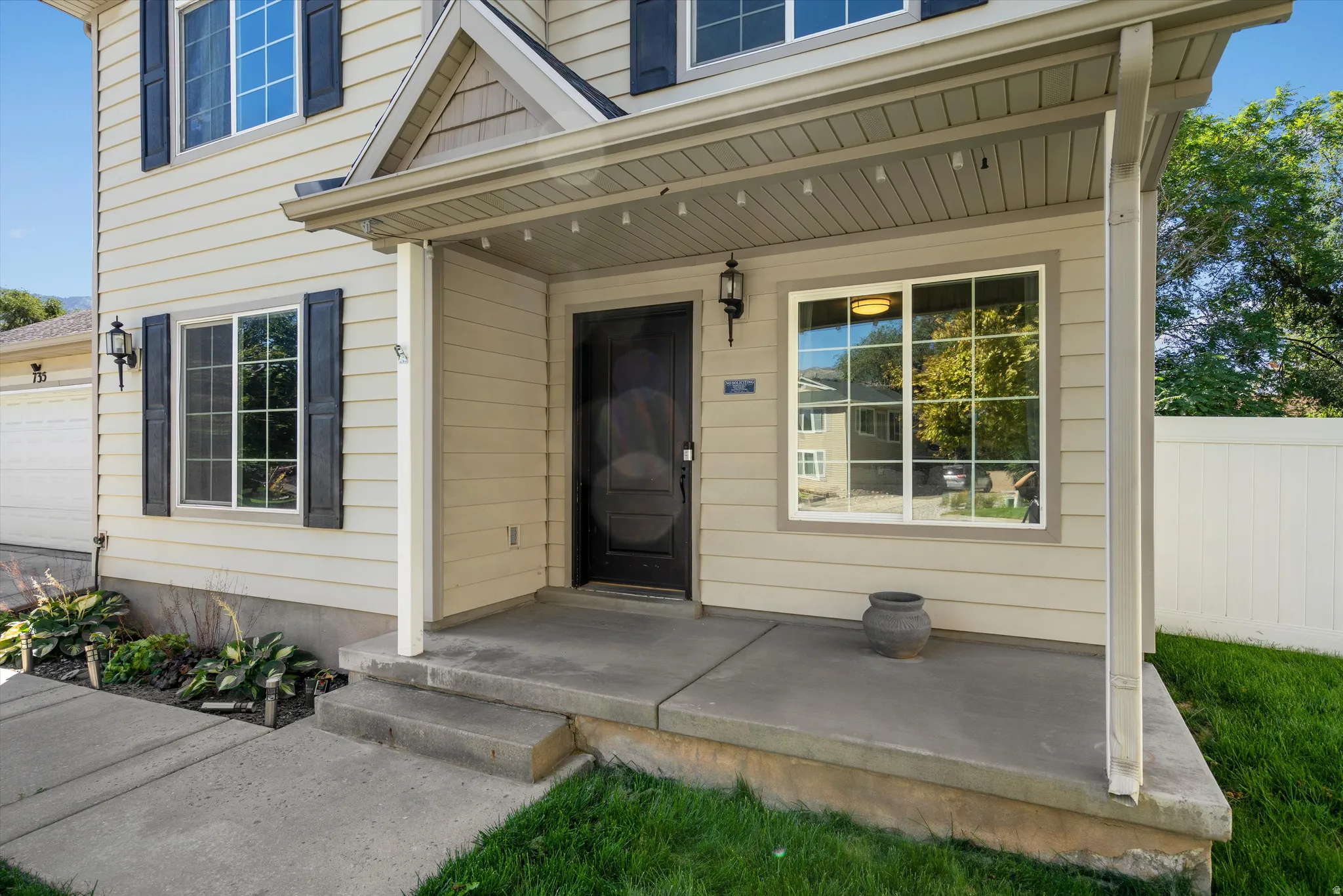 Exterior featuring neutral-toned siding, black shutters, and a covered concrete porch