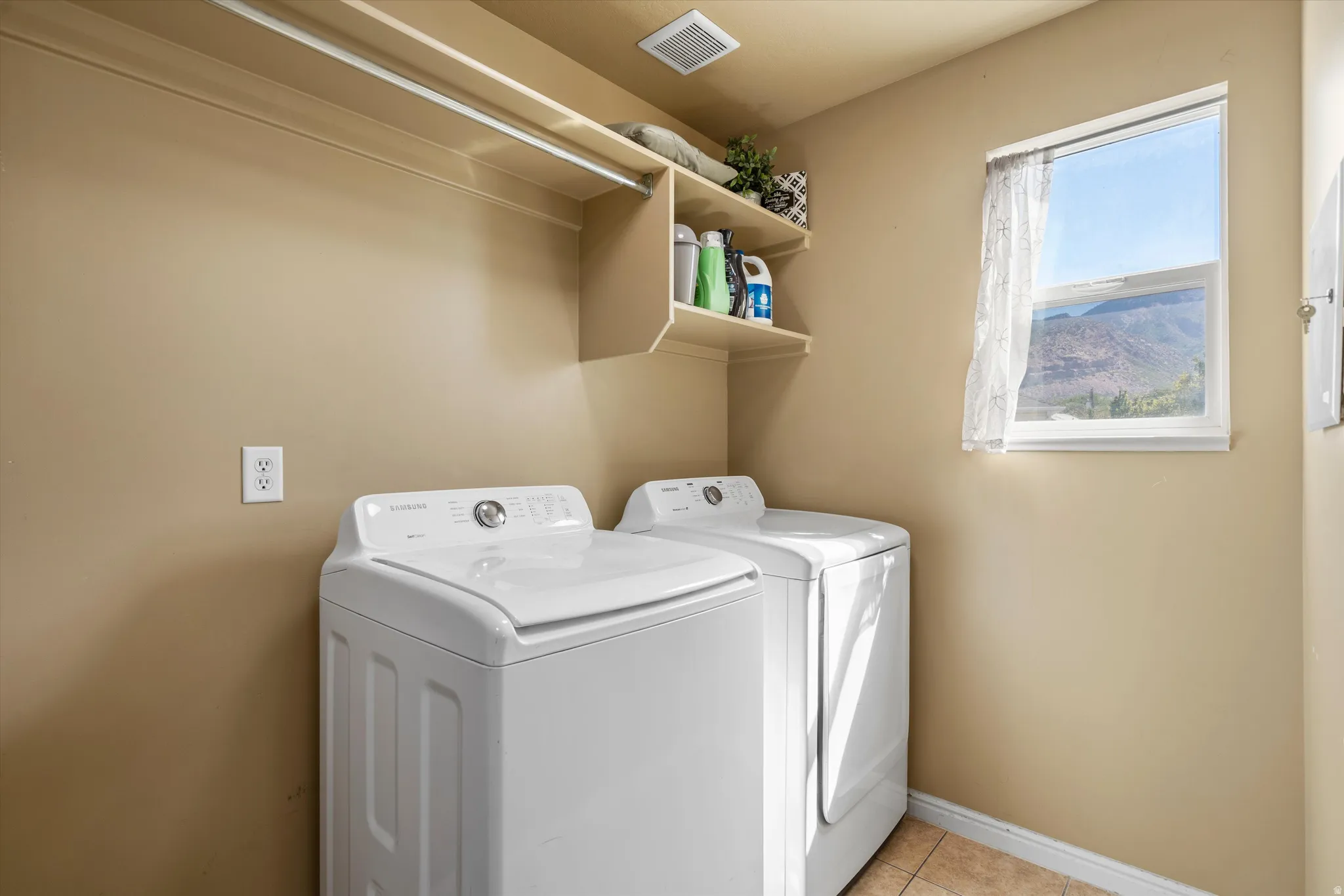 Built-in shelving, mounted clothes hanging rod, window, and tile flooring