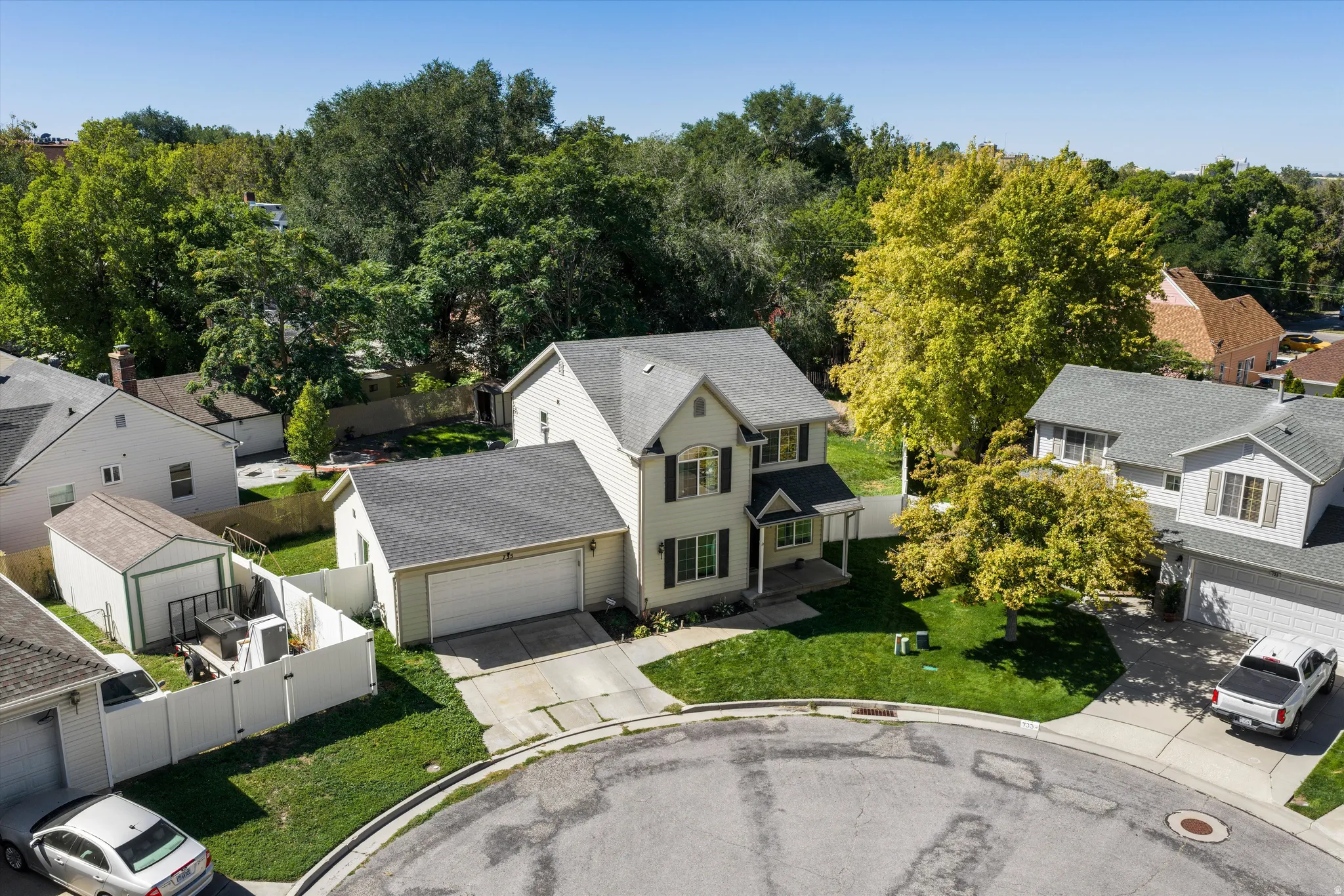 Two-story residence with a two-car attached garage, mature landscaping, and a fenced backyard