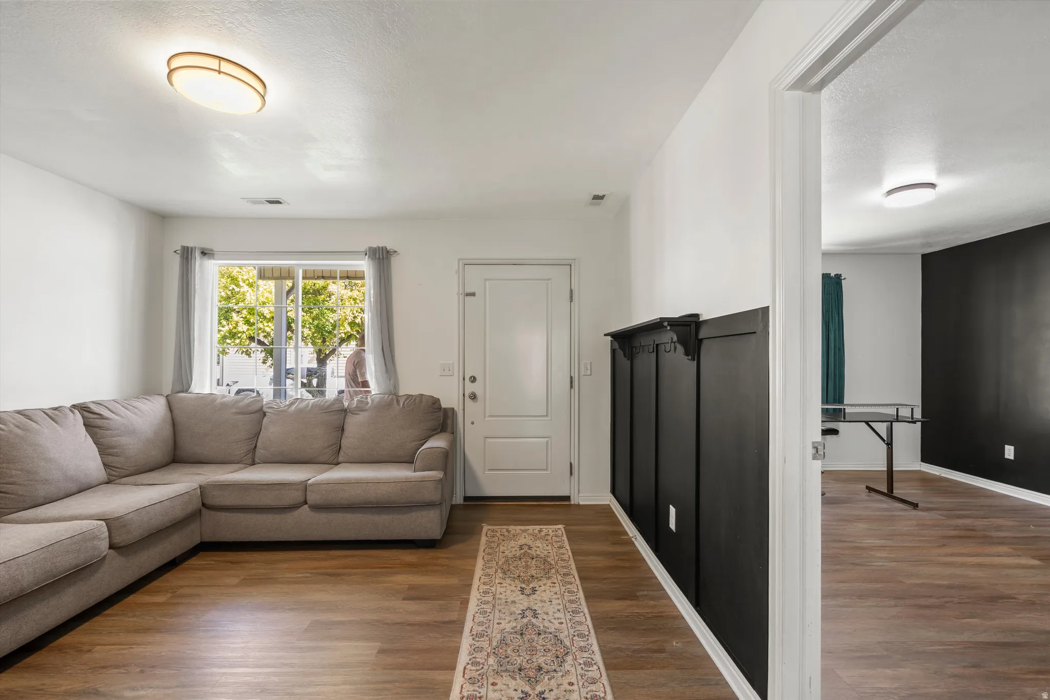 Wood-finish flooring, white walls, and a contemporary ceiling light fixture define this living area