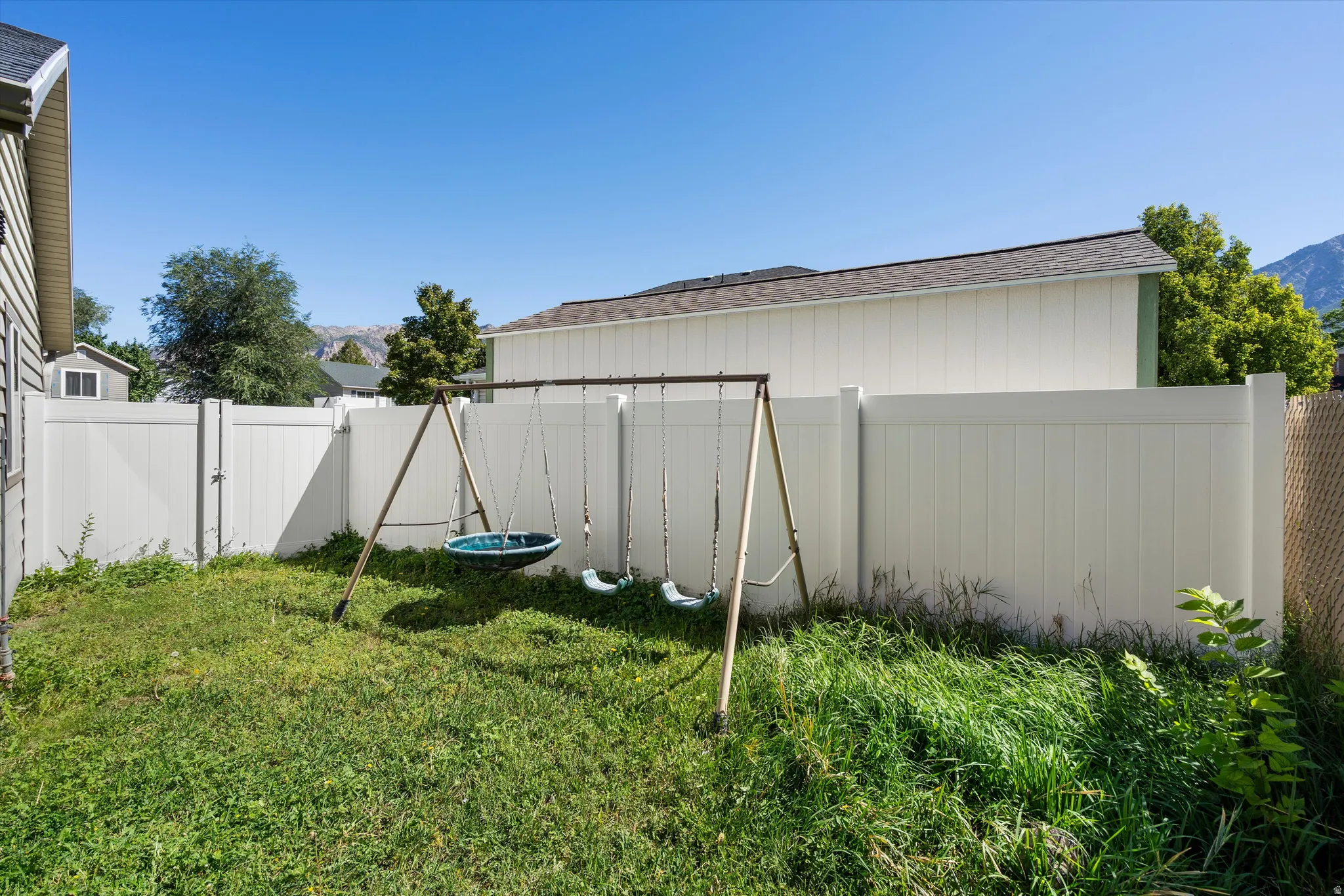 Enclosed backyard with white privacy fencing and a distant mountain backdrop