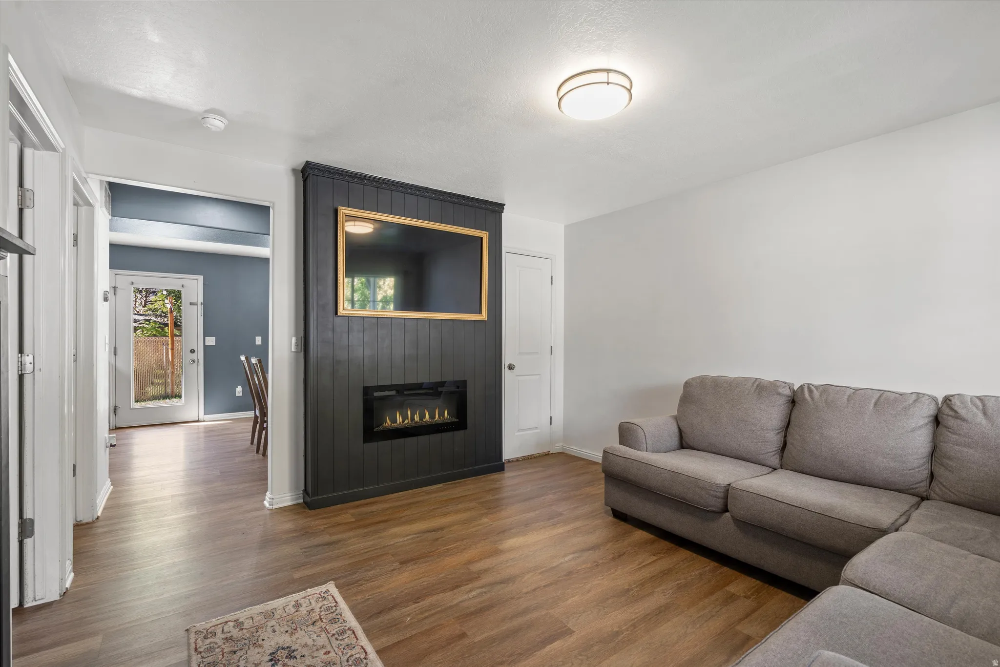 Wood-finish flooring throughout, featuring a built-in electric fireplace and a black shiplap accent wall
