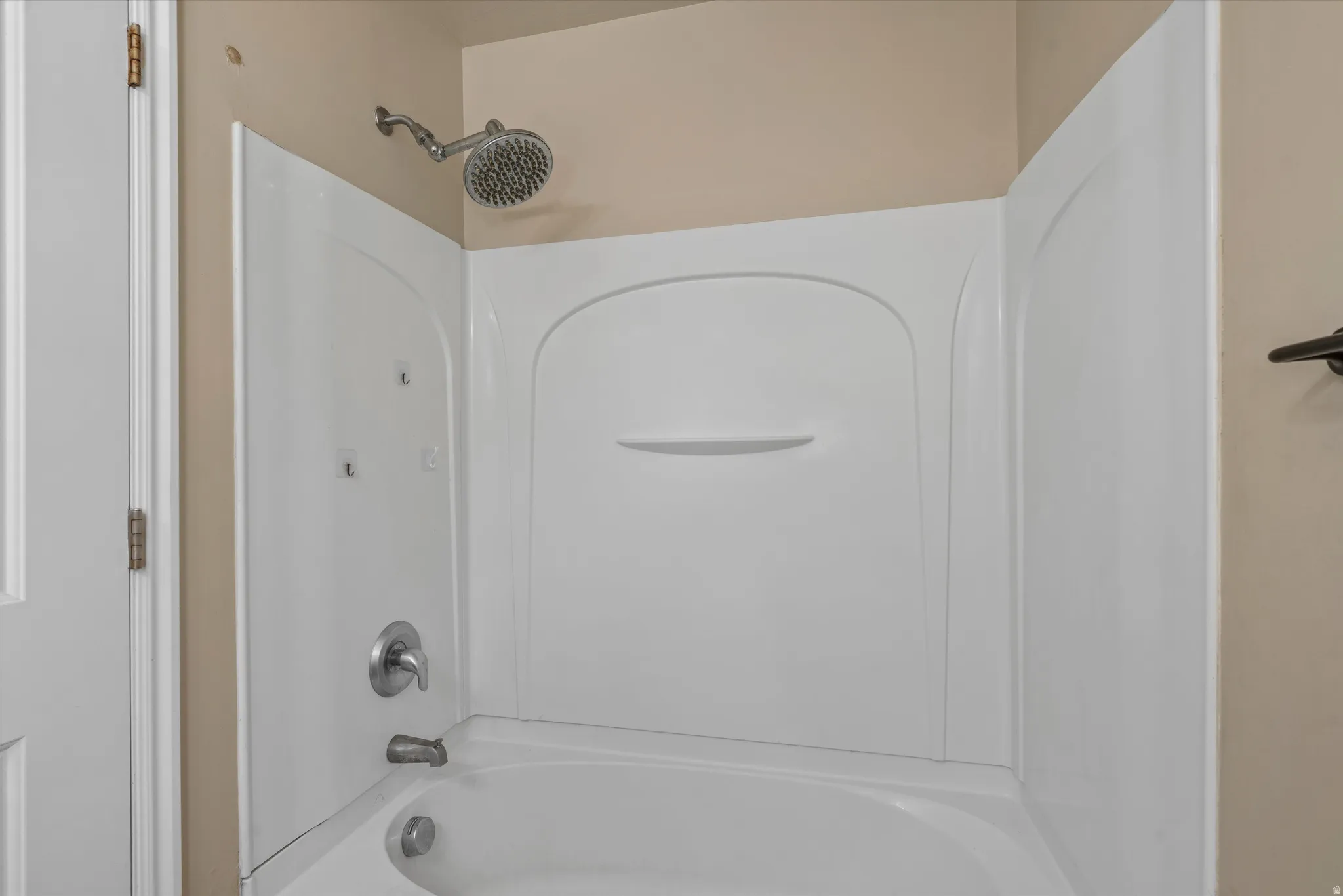 Bathtub and shower combination with white surround, chrome fixtures, and a rain showerhead