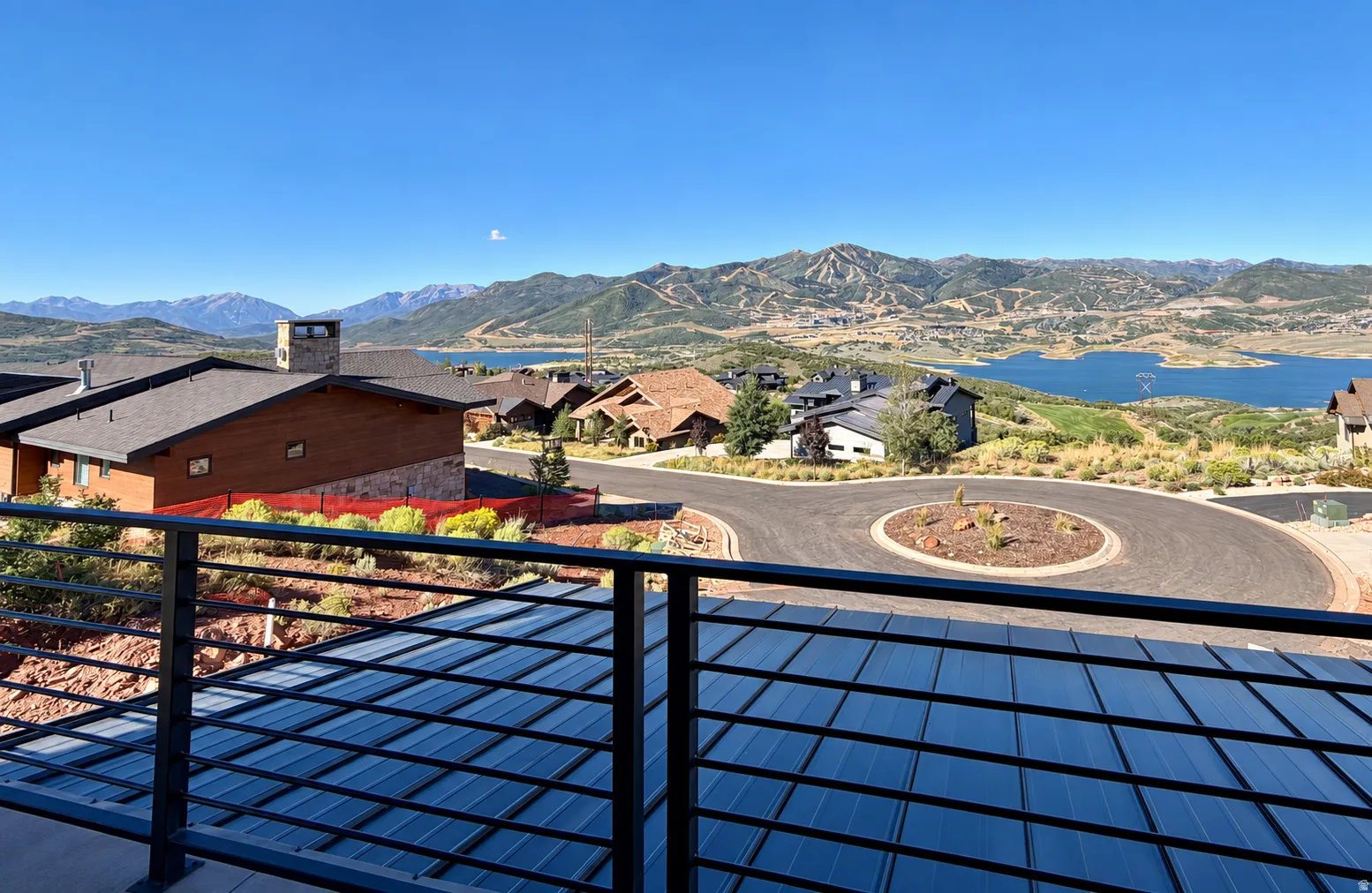 Expansive mountain and lake scenery with a contemporary metal railing