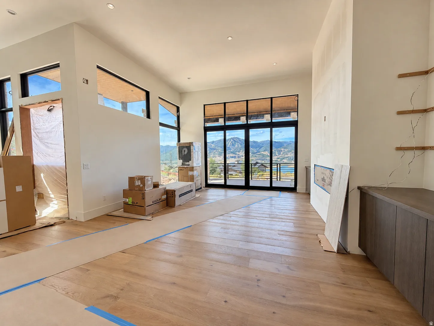 Expansive room featuring high ceilings, wood-finish flooring, a wall of glass doors, and recessed lighting