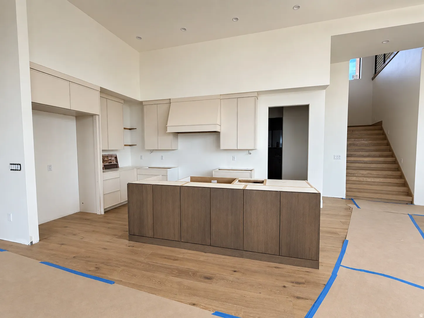 Kitchen featuring a wood-finish island, light-toned cabinetry, and complementary wood-finish flooring