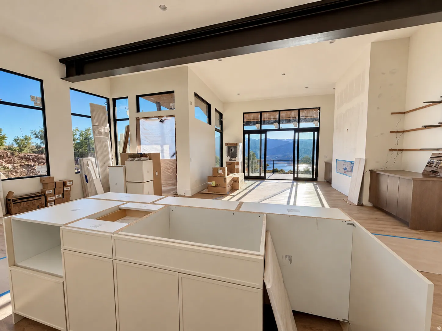Open concept interior with high ceilings, exposed structural beam, and multiple large windows