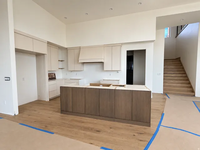 Kitchen featuring a wood-finish island, light-toned cabinetry, and complementary wood-finish flooring
