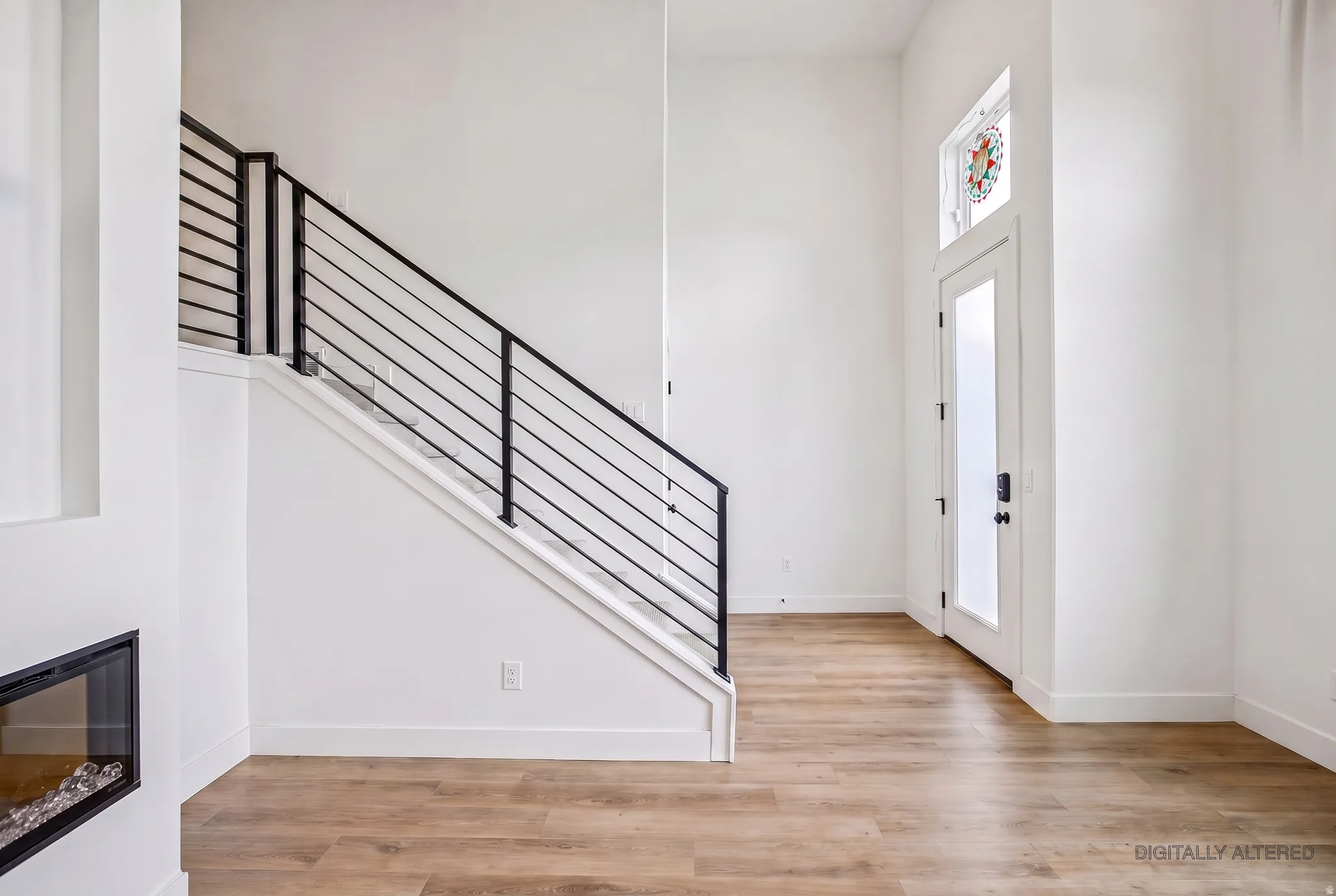 Wood-finish flooring with a modern staircase featuring horizontal metal railings