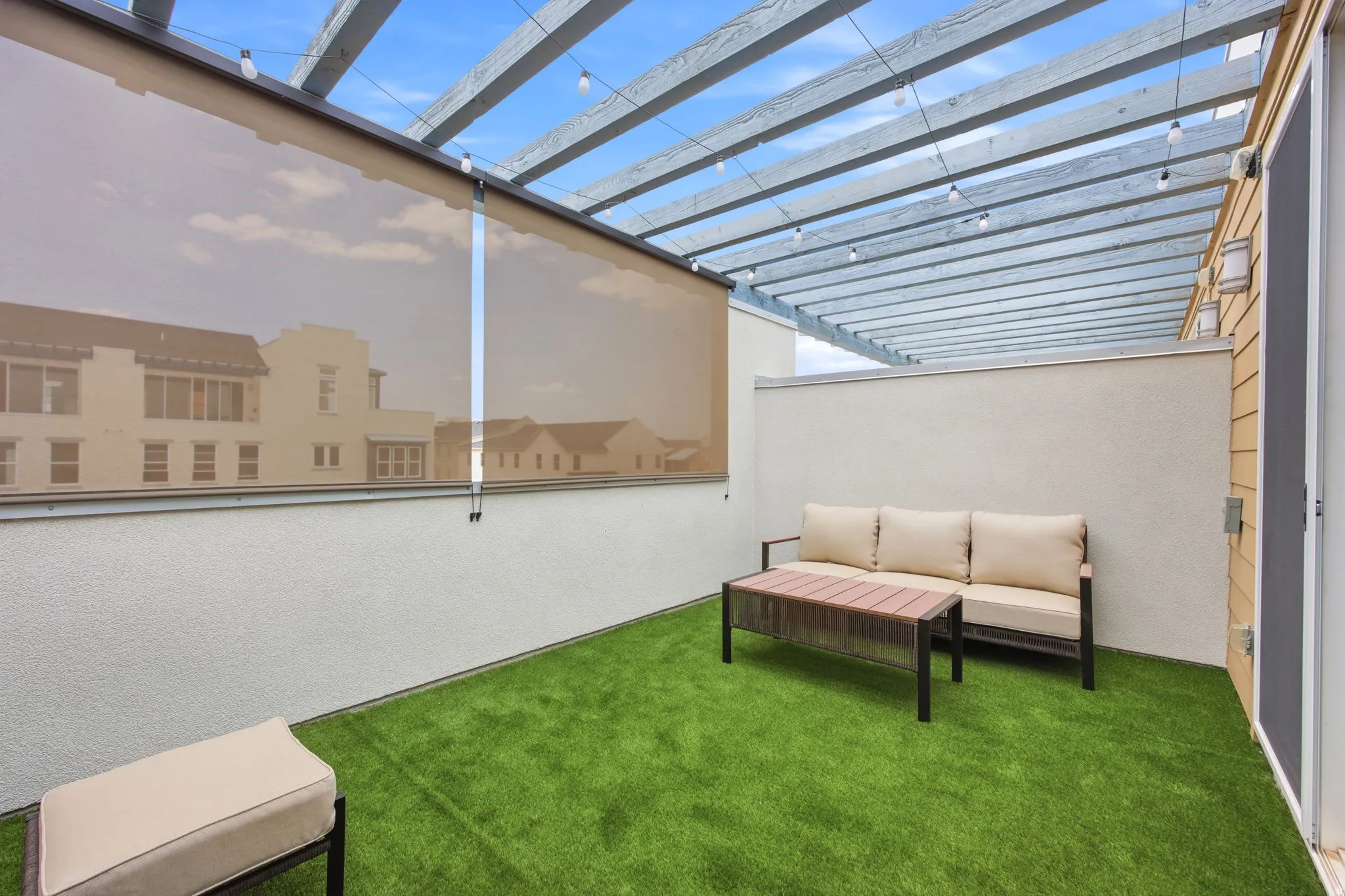 Rooftop patio featuring a slatted pergola, roll-down shade, and turf flooring