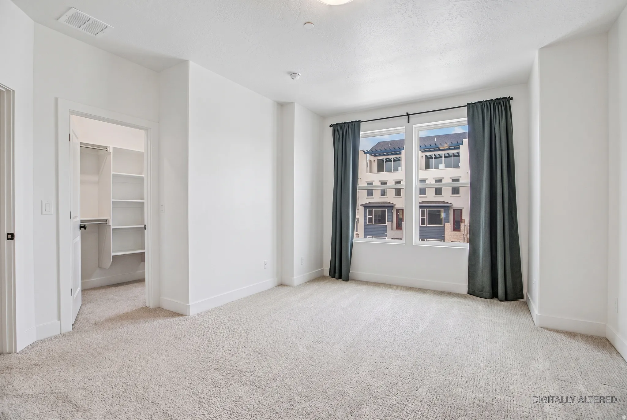 Carpeted room with white walls, a built-in closet with shelving, and large windows