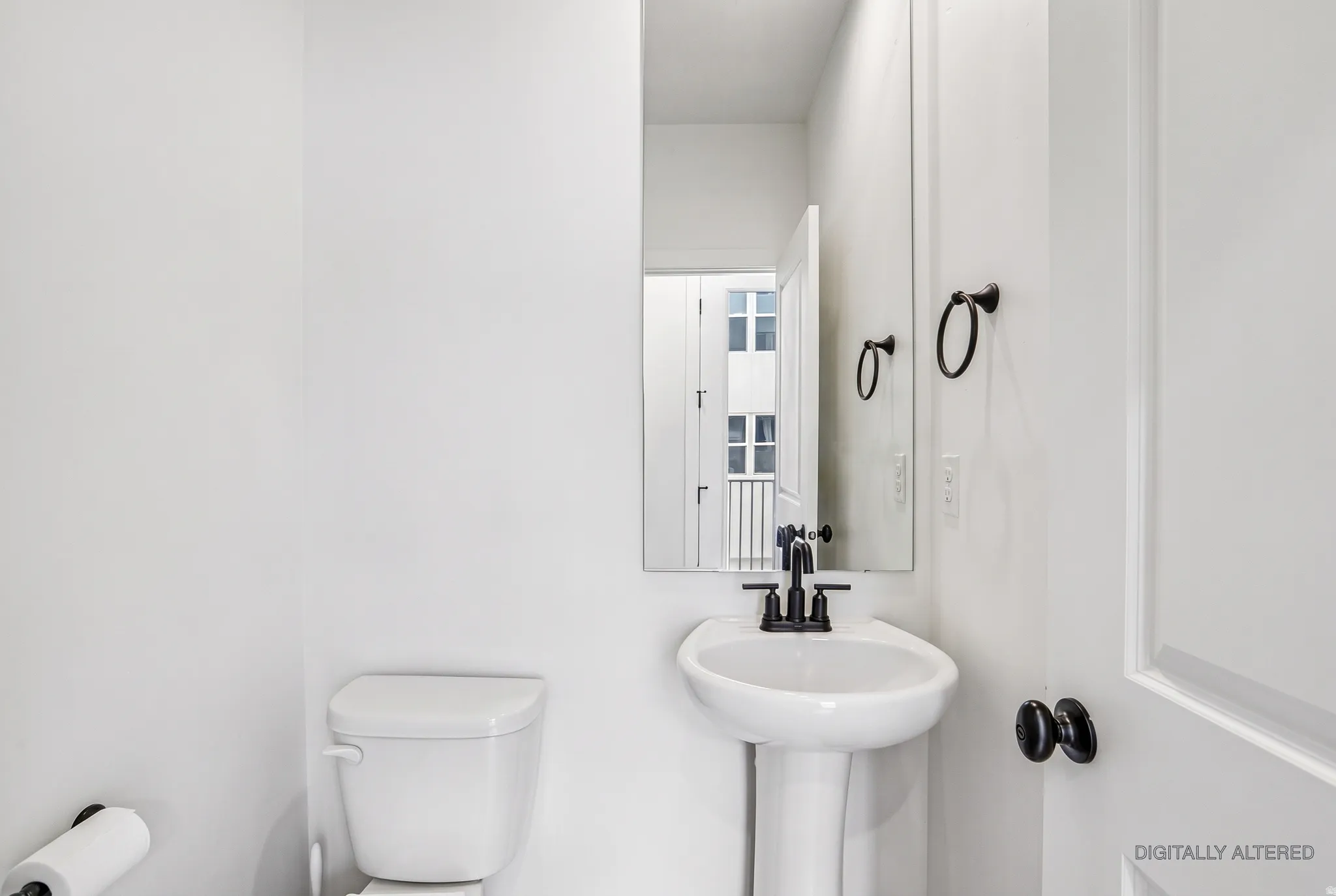Pedestal sink with a matte black faucet, wall-mounted mirror, and black hardware