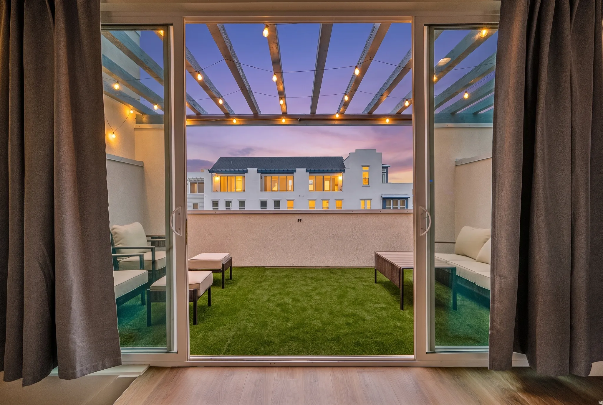 Rooftop patio featuring artificial turf, a pergola, and string lighting