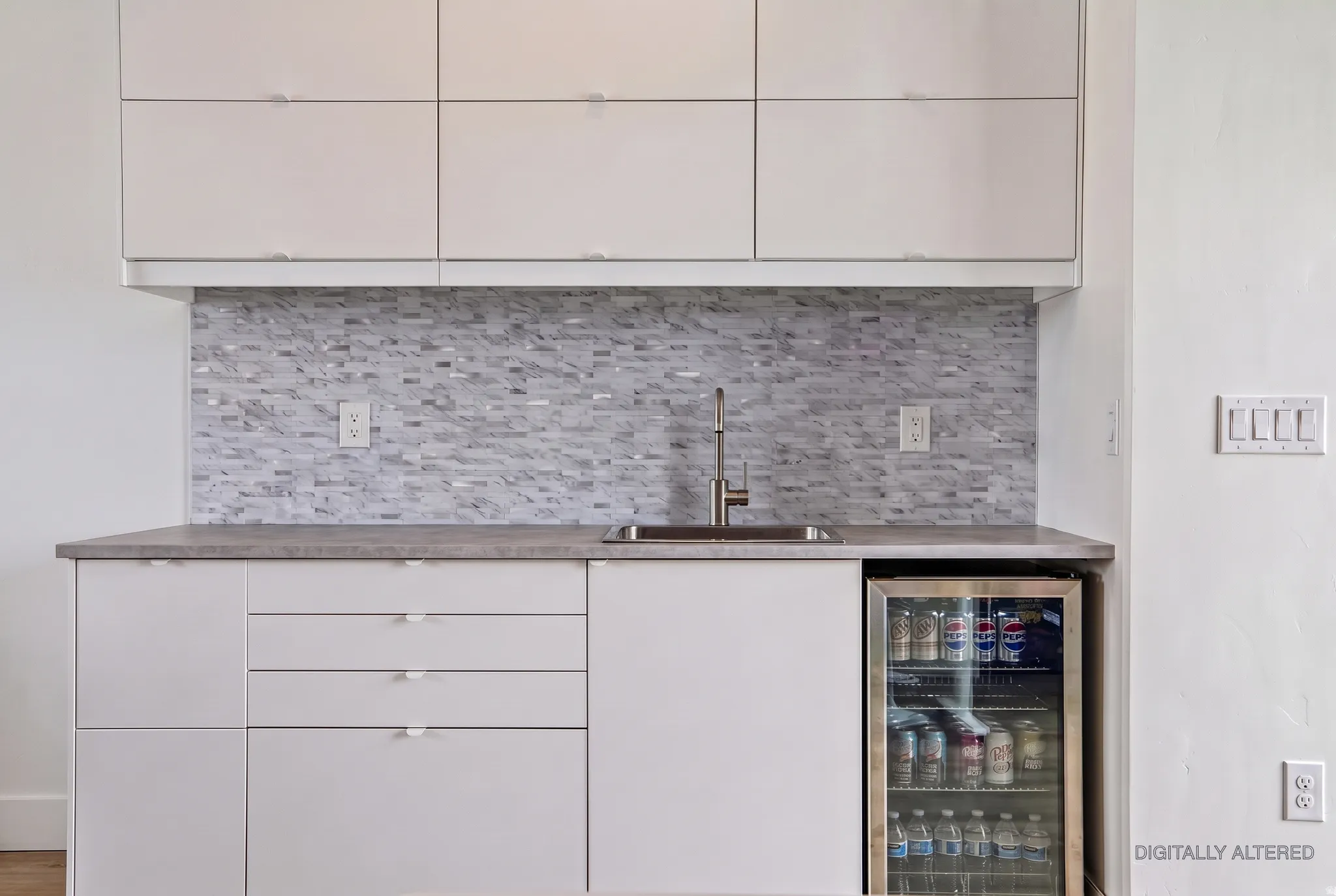 Integrated beverage refrigerator, under-mount stainless steel sink, sleek upper and lower cabinetry, mosaic tile backsplash, and a neutral countertop