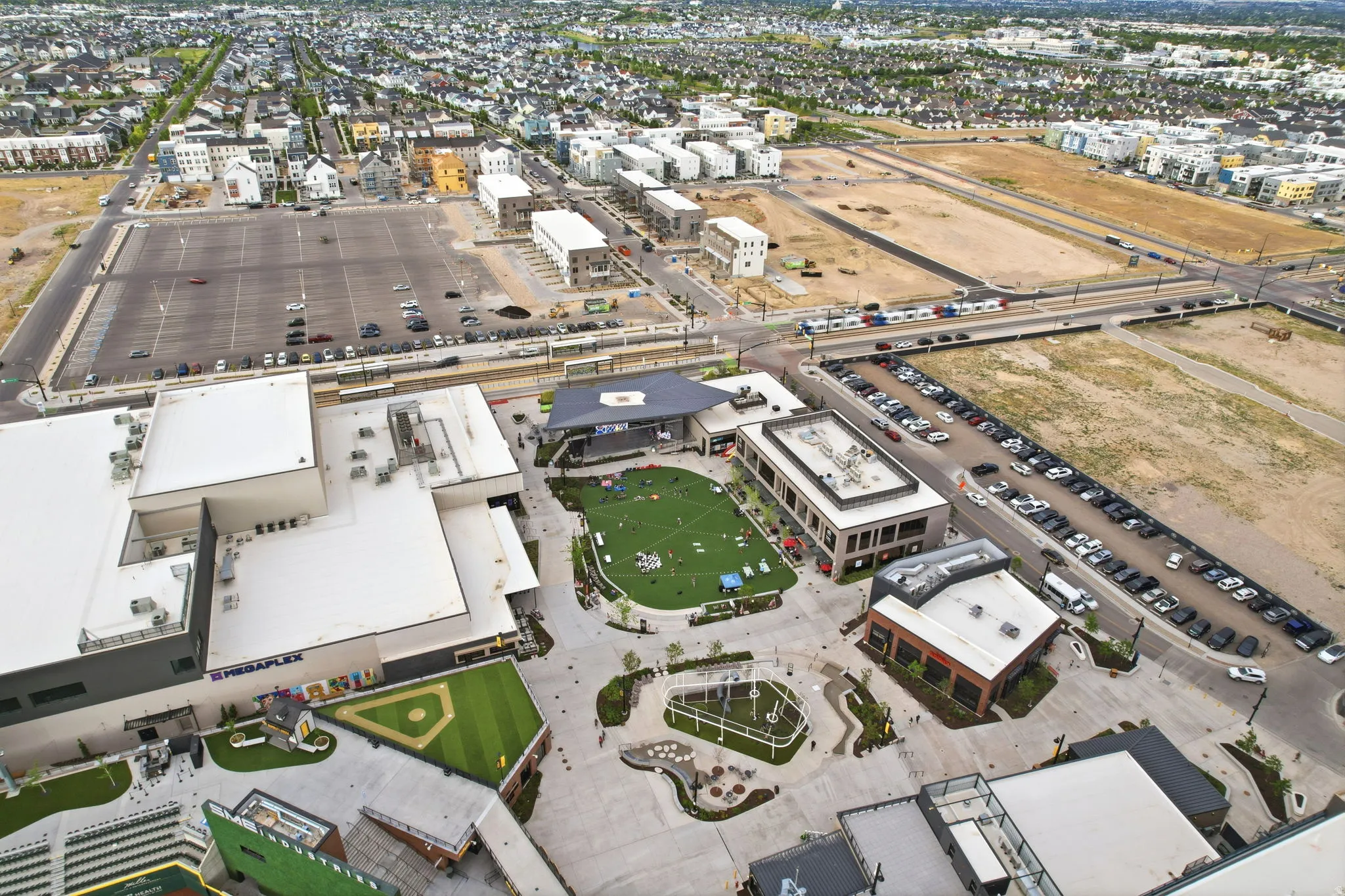 Aerial perspective showcasing a mixed-use development with commercial structures, surface parking areas, and a central green space