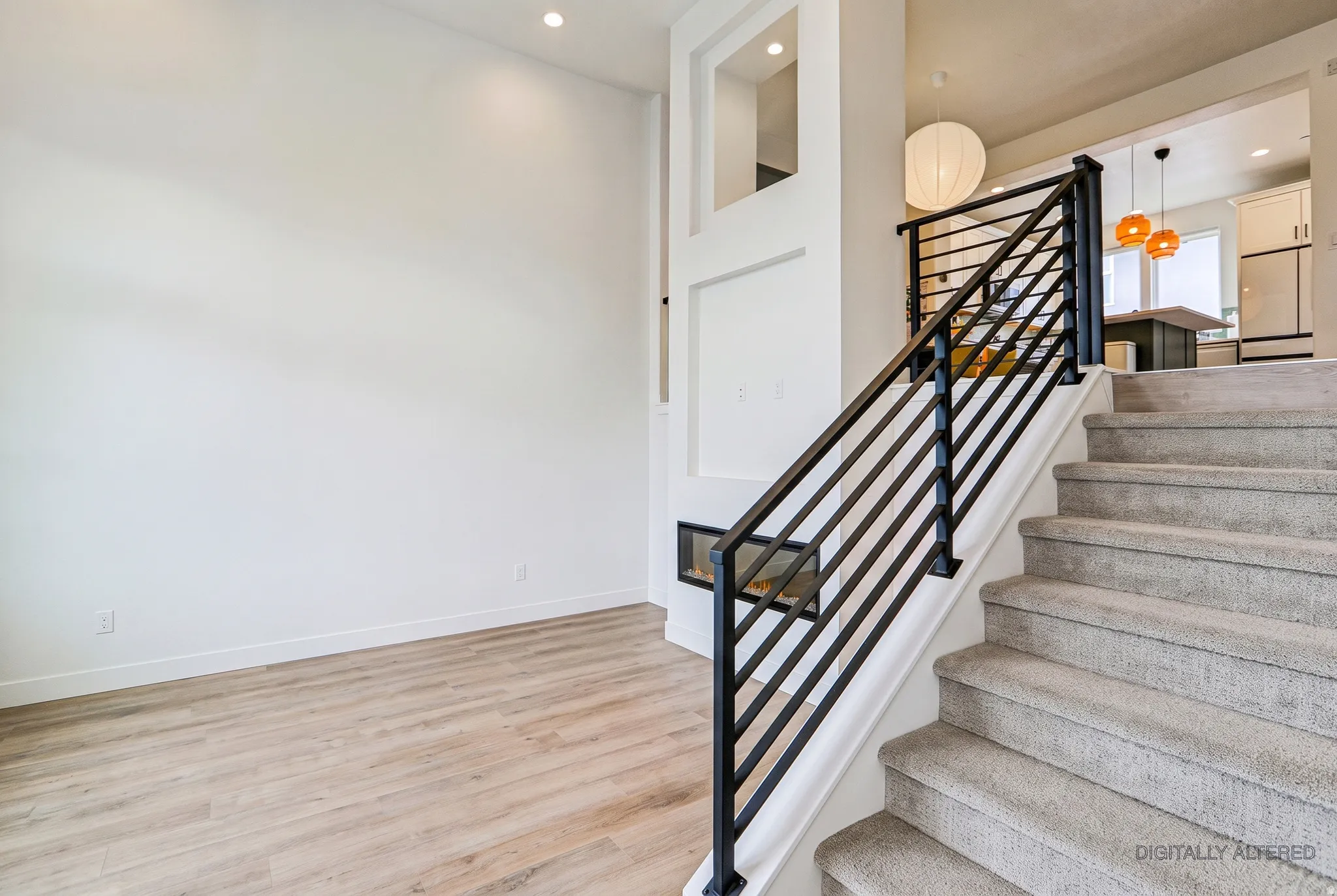 Modern interior with wood-finish flooring, a linear fireplace, and a carpeted staircase with an iron railing