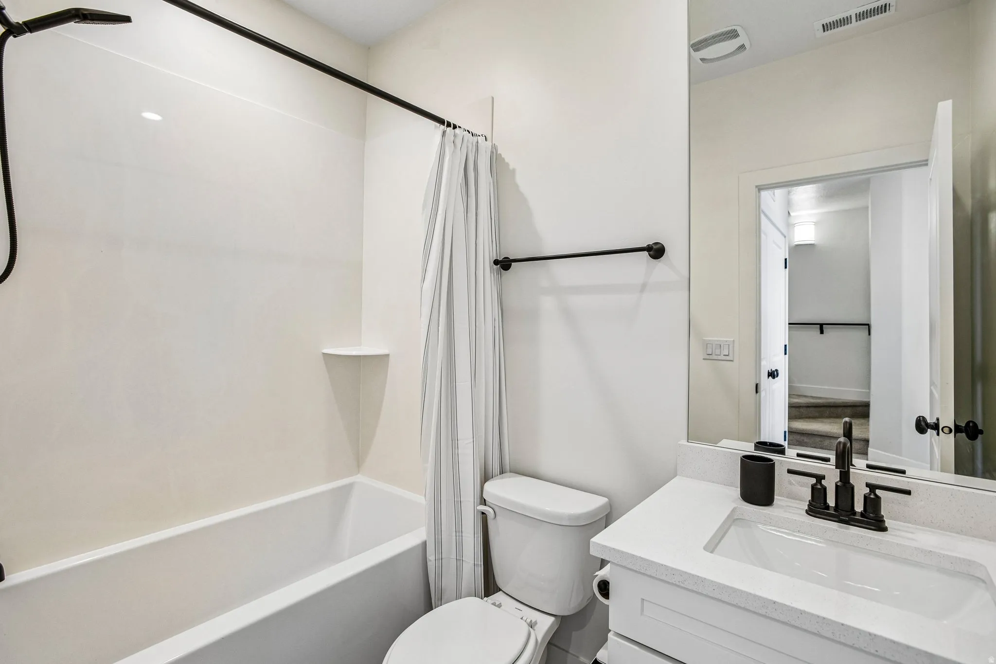 Bathroom featuring a white vanity with a rectangular sink, speckled countertop, and matte black faucet