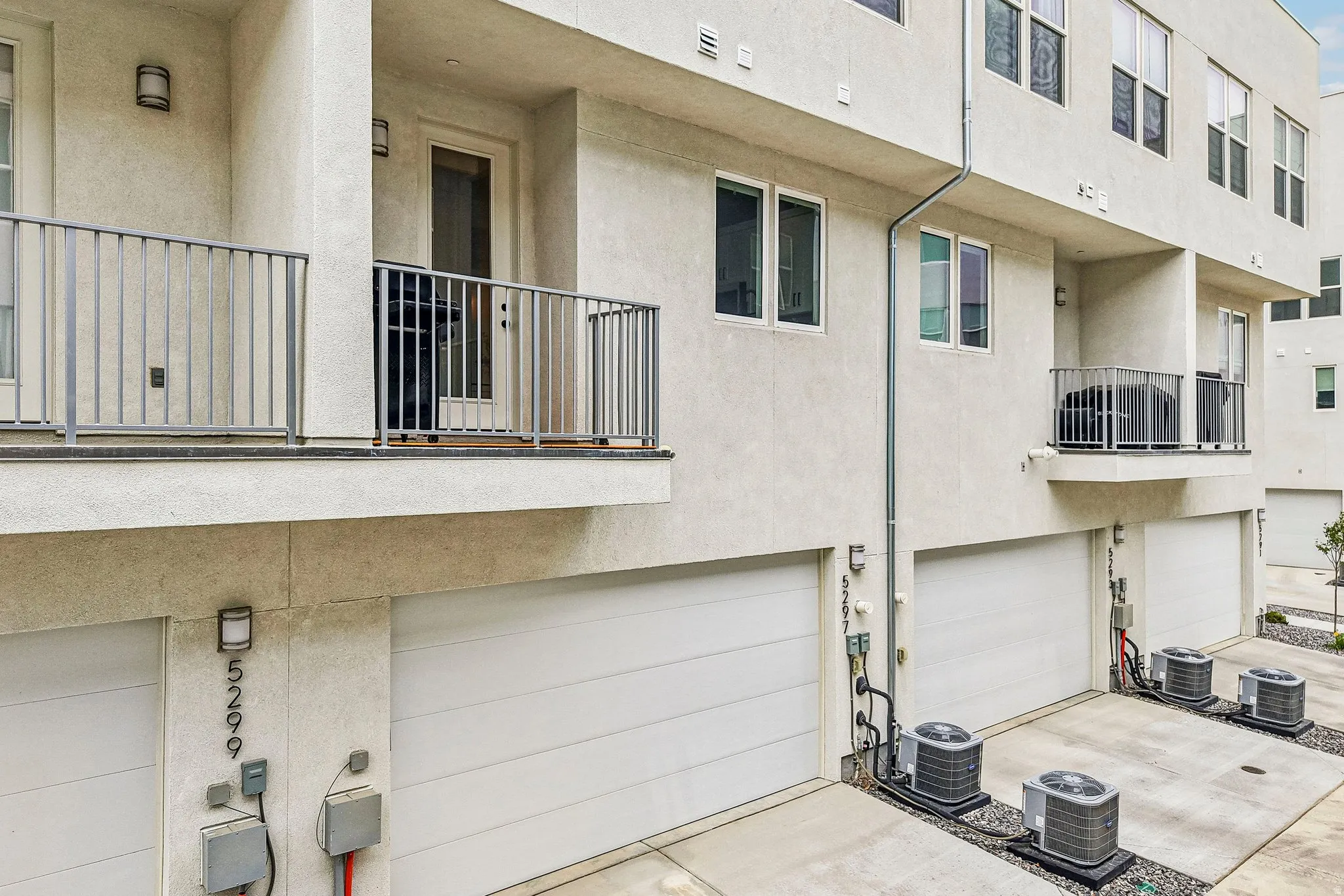 Multi-level stucco exterior with multiple balconies featuring metal railings