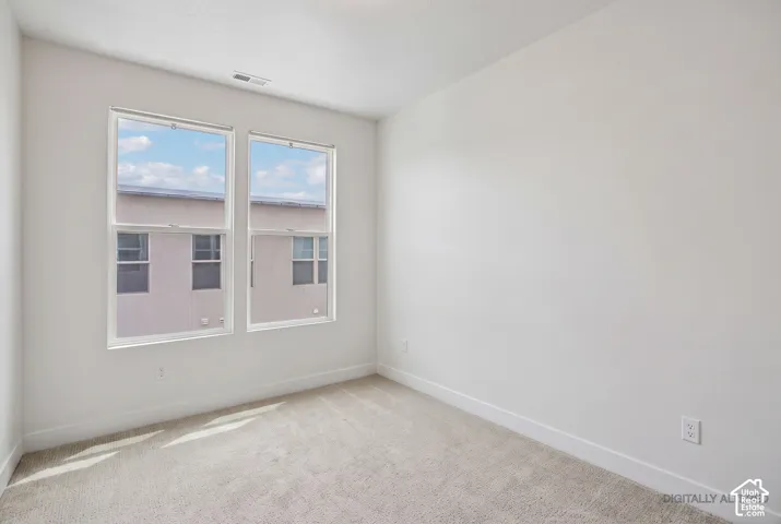 Light-toned carpeting, white walls, and dual vertical windows