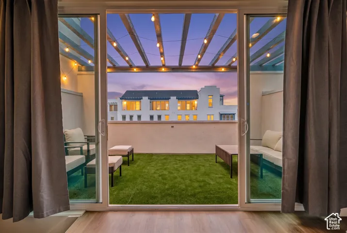 Rooftop patio featuring artificial turf, a pergola, and string lighting