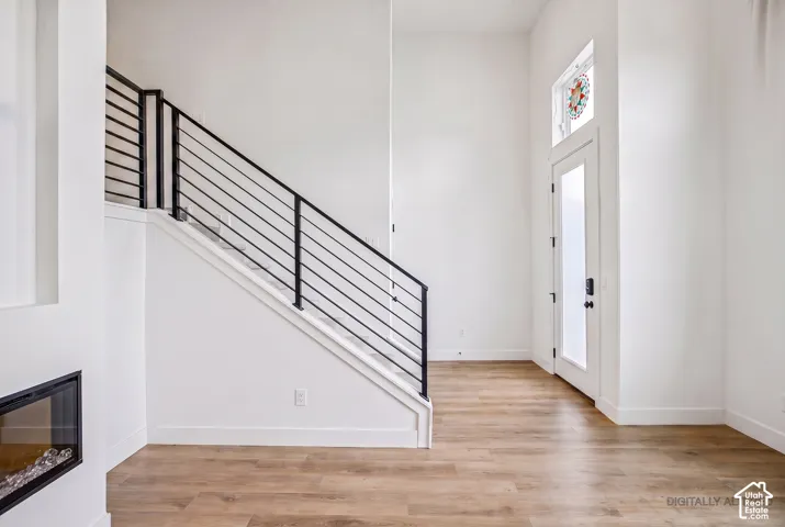 Wood-finish flooring with a modern staircase featuring horizontal metal railings