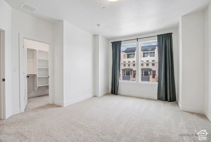 Carpeted room with white walls, a built-in closet with shelving, and large windows