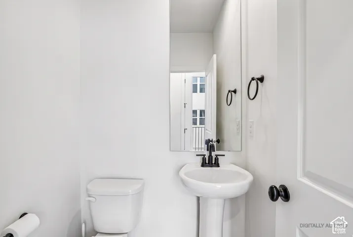 Pedestal sink with a matte black faucet, wall-mounted mirror, and black hardware