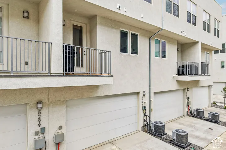 Multi-level stucco exterior with multiple balconies featuring metal railings