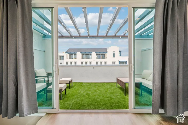 Expansive outdoor patio with artificial turf, overhead pergola, and multiple seating areas