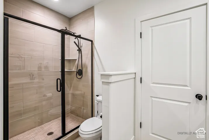 Enclosed shower with matte black fixtures, tile surround, recessed shelf, and tiled shower pan