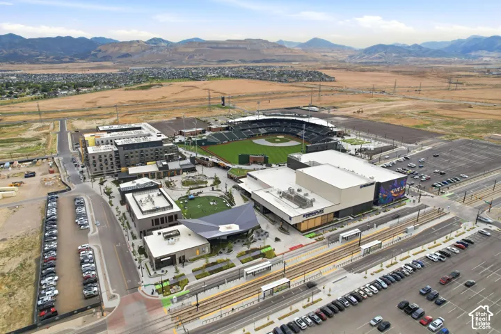 Mixed-use development featuring multi-story residential buildings, commercial structures, a baseball stadium, and a light rail system with platforms