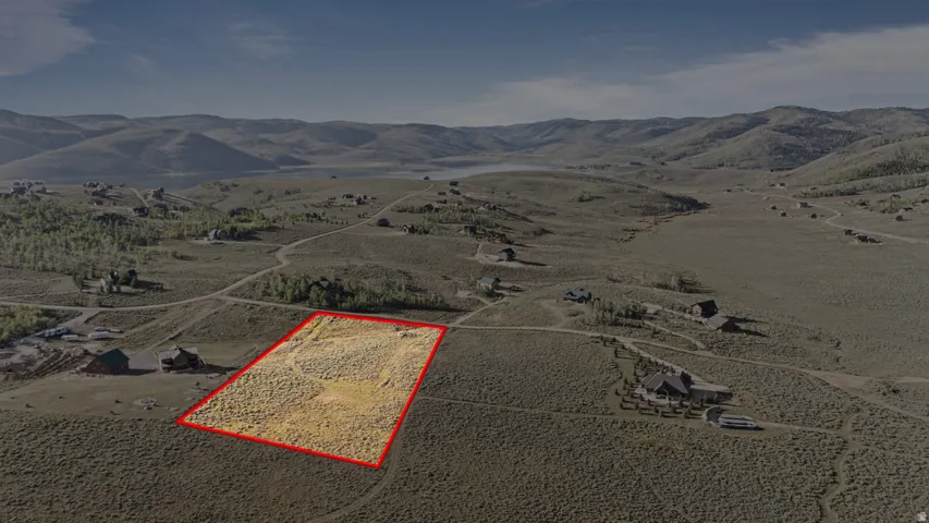 Expansive land parcel with surrounding topography, distant water features, and scattered residential properties