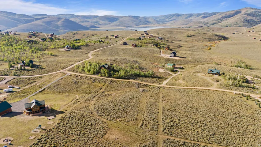 Expansive hillside property featuring scattered residences, natural landscaping, and distant water body
