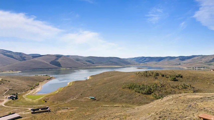 Expansive water body surrounded by rolling hills and scattered trees