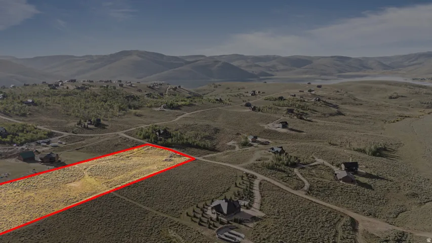 Expansive land parcel with surrounding residential properties, surrounded by rolling hills and distant mountains