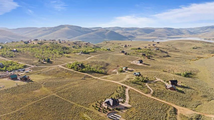 Expansive, undeveloped land featuring multiple residential structures and unpaved roadways