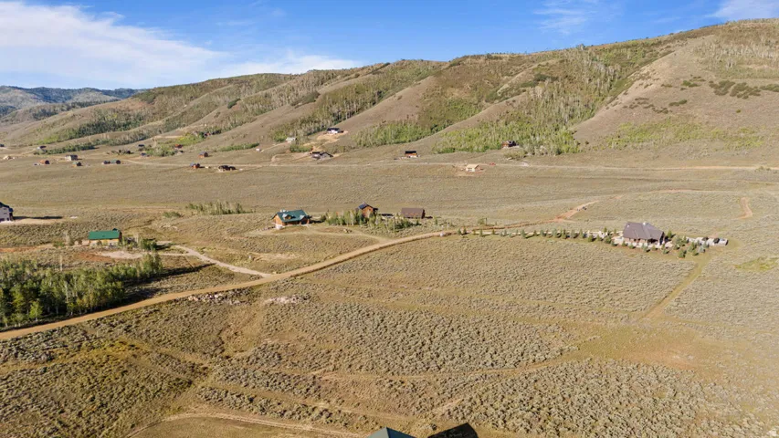 Expansive landscape with a prominent residential structure, surrounded by natural vegetation and distant hills