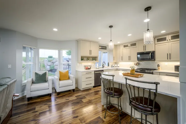 Kitchen featuring wood-finish flooring, light-toned cabinetry with dark hardware, a white countertop island, pendant lighting, and recessed ceiling lights